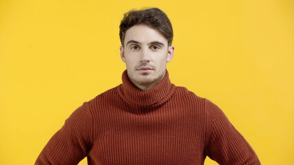 Fototapeta premium Brunette man in sweater looking at camera isolated on yellow