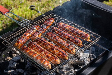 Grilled sausages on the charcoal grill, summer picnic in nature, barbecue bbq grill traditional German bratwurst hot dogs 
