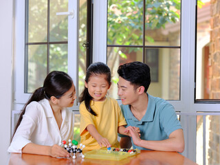 Happy family of three doing molecular structure model together