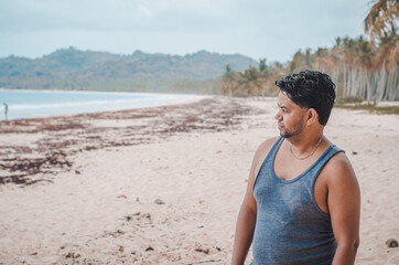 Latin man with dark skin on the beach looking at the landscape in flannel