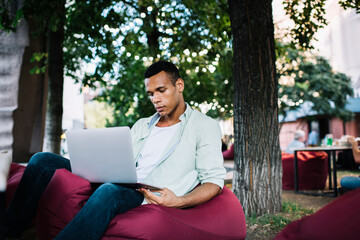 Fototapeta premium Confident African American guy with laptop in park
