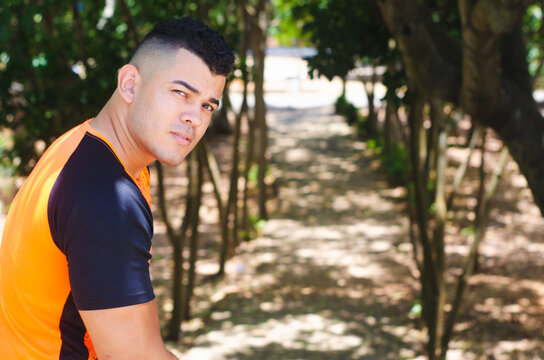 White-skinned male model of Venezuelan origin in the Dominican Republic. sexy man in jeans in the park outdoors with orange walks with natural sunlight among the leaves sitting on the stairs