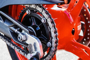 A fragment of the rear wheel of a motorcycle with a chain and a sprocket. Selective focus. Close-up