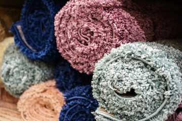 Small carpets in rolls made of synthetic material. Trade in floor coverings in a specialized store. Close-up