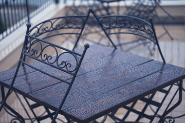 Fototapeta na wymiar black iron metal chairs near table on rainy outdoor terrace