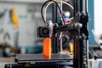 The 3D printer prints orange plastic model
