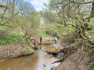 Tourists on a fallen tree cross Protva River in Kaluga region. Russia