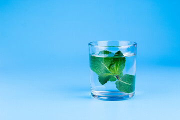 Fresh water in glass with mint on aqua blue background. Part of set.