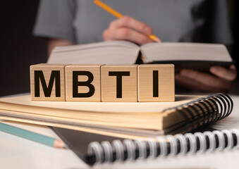 MBTI acronym, word on wood blocks on desk with books. Psychological study and research concept.