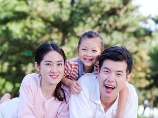 Happy family of three on the park grass