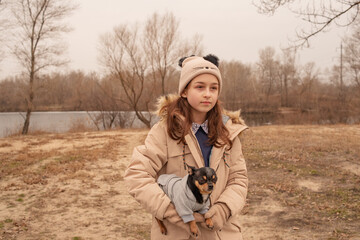 Teenage girl and chihuahua dog. A girl in a beige jacket and a beige hat.