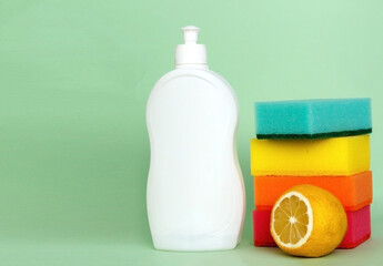 Bottle of dishwashing liquid, sponges and lemon on color background.
