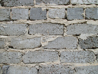Background from an old gray wall made of bricks. The texture is rough with seams. 
