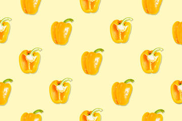 Seamless pattern of whole and halved yellow peppers on a yellow background