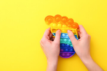Trendy popular silicone colorful anti stress Pop It toy for child on yellow background.