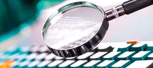 Closeup images of magnifying glass on laptop keyboard