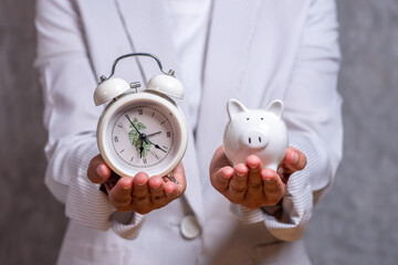 Businessman with an alarm clock and piggy bank time and money concept