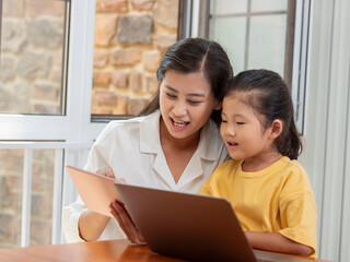 Fototapeta premium Young Happy mother and daughter use tablet