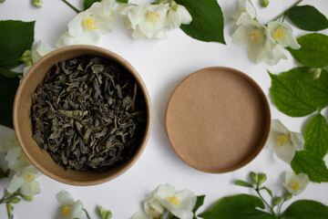 Fototapeta na wymiar Leaf tea with jasmine in a round carton on white background. Zero waste concept