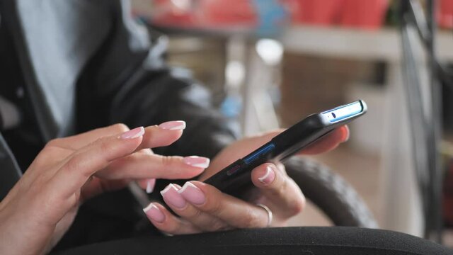 hand of a young woman using a mobile phone reads a phone message or downloads a smartphone app