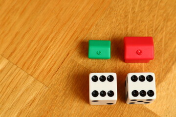 Double six with dices next to small red and green houses. Close up and isolated. Concept of luck and easy to lose. Wooden background. Stockholm, Sweden, Europe.