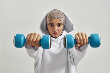 Young arabian woman in hijab holding dumbbells