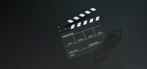 Fototapeta na wymiar Clapper board or movie slate with black face mask or medical mask isolated on black background.