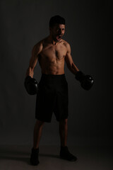 Fototapeta na wymiar Young strong boxer fighting in shadows