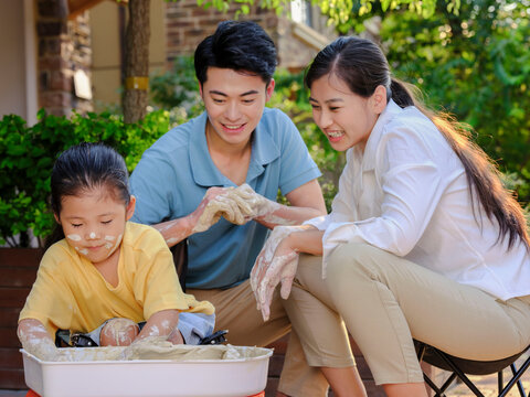 Happy family of three doing pottery together outdoors
