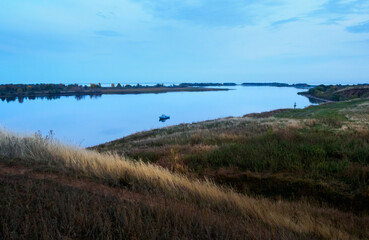 Lone boat anchored in the bay, evening on the river, countryside.