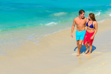 Young beautiful couple walking and relaxing on the beach 