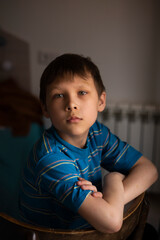 Portrait of a serious boy, sitting by the window. Selective Focus