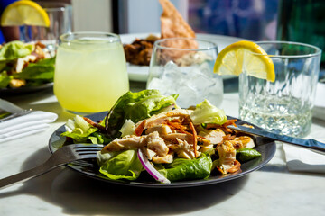 Caesar salad in two plates on a round table in a restaurant or cafe with a panoramic window on a sunny day
