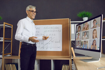 Happy male teacher having online class with group of distant students. Smiling mature man standing...