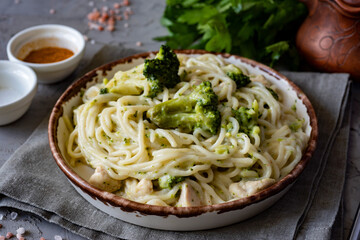 A hearty vegetarian lunch: spaghetti with broccoli and cream sauce in a beautiful plate on a gray background. - Powered by Adobe
