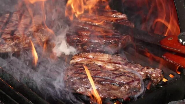 Searing and flipping ribeye steaks on grill 2