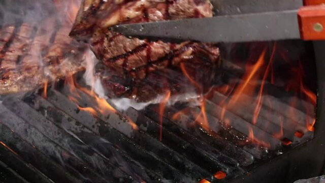 Searing and flipping ribeye steaks on grill 3