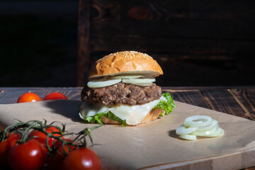 Burger made it at home. Next to it are red tomatoes on a branch. Close-up.