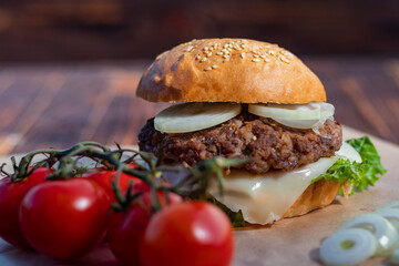 Burger made it at home. Next to it are red tomatoes on a branch. Close-up.
