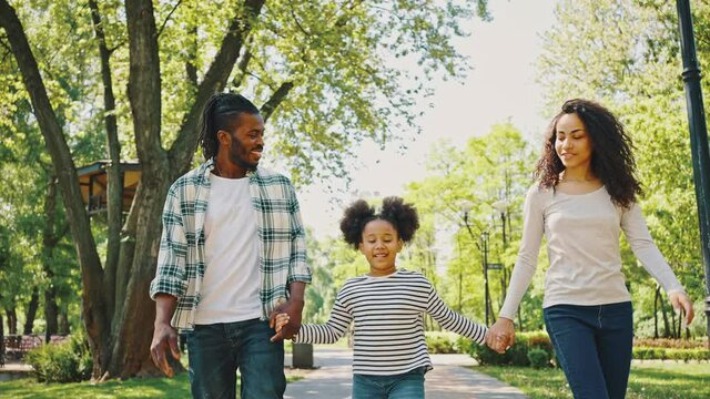 Cloce up African American family walking in the park holding hands and smiling. Have fun during a family weekend