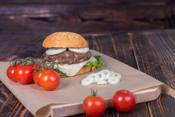 Burger made it at home. Next to it are red tomatoes on a branch. Close-up.