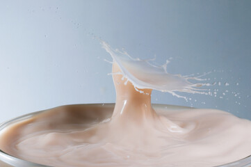 Efeito de gota caindo em copo cheio de leite congelando  um momento e formando uma coroa. 