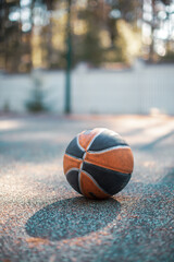 Basketball ball lying on court surface outdoor in sunlight. Advertising photo for sportive equipment store