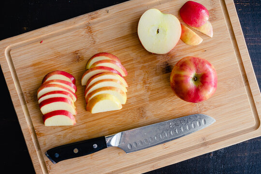 Sliced Honeycrisp Apples on a Bamboo Cutting Board: Slices of red apples on a wooden carving board