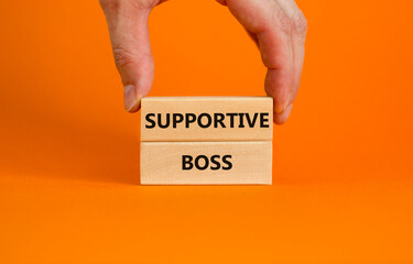 Supportive boss symbol. Wooden blocks with words 'Supportive boss' on beautiful orange background. Businessman hand. Business and supportive boss concept. Copy space.