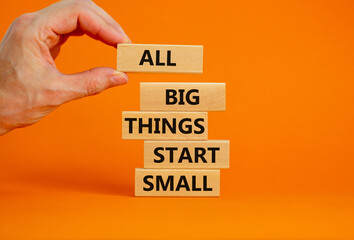 Business concept growth success process. Wood blocks on orange background, copy space. Businessman hand. Words 'all big things start small'. Conceptual image of motivation.