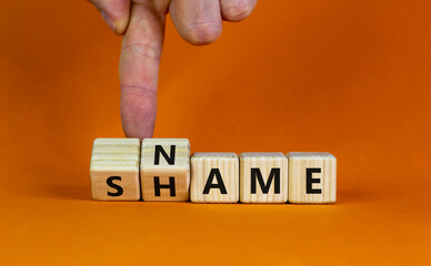 Name or shame symbol. Businessman turns wooden cubes and changes the word 'shame' to 'name' or vice versa. Beautiful orange background, copy space. Business, name or shame concept.