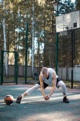 Professional male american basketball player training, warming up on court outdoors in summer. Energetic workout