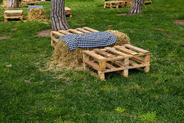  picnic spot on green grass on a summer day with straw tables and wooden boxes