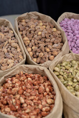 Almonds and pistachios with spices lie in paper bags on the counter.